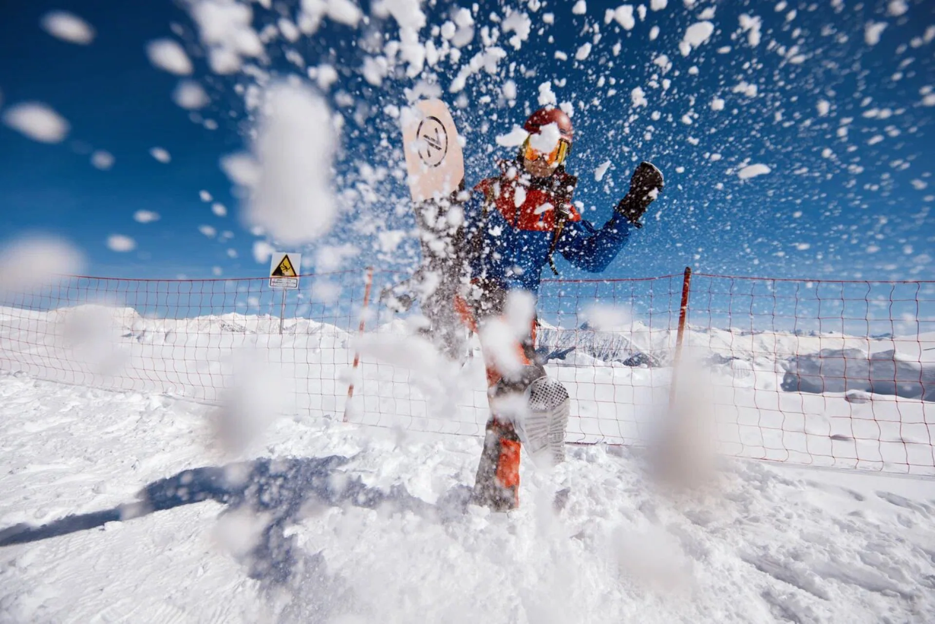 Лыжник поднимает облако снега во время спуска
